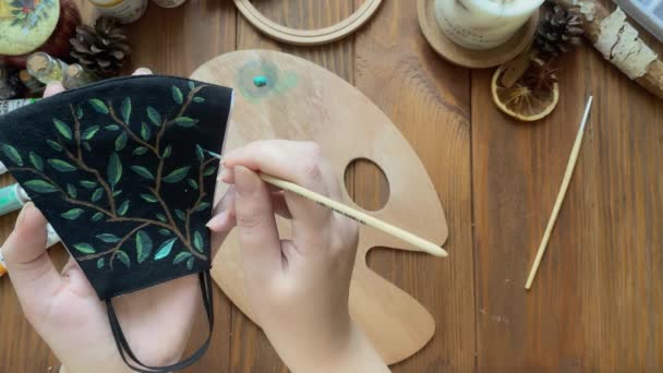Руки людей малюють листя на медичній масці пензлем і фарбою . — стокове відео