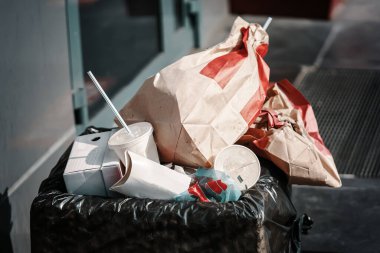 Bir deste kağıt paket, bir fincan kahve ve diğer içecekler çöpte.