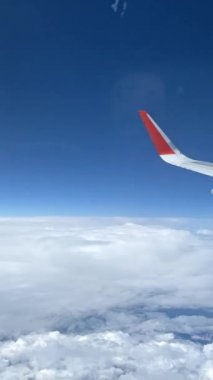 Bulutların üzerindeki uçak penceresinden ve uçağın kanadından görüntüle.
