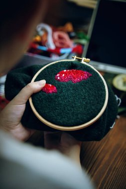 Kız yeşil kumaşa mantar kapağı işliyor..