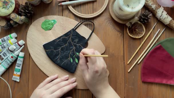 Chica dibujar hojas en la máscara de tela médica con pincel y pintura. — Vídeo de stock