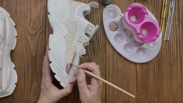 妇女在桌面上用刷子画白色靴子. — 图库视频影像