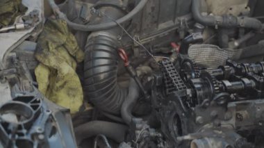 Tamirci araba motoruna makara vidalıyor.