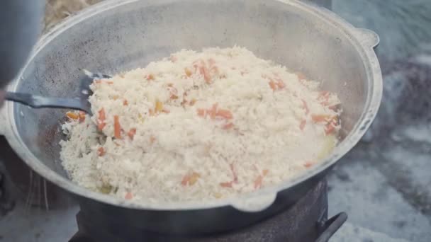 Chef mezcla pilaf y caldo en kazan con cuchara ranurada. — Vídeos de Stock