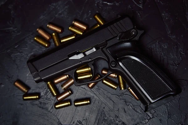 Pistola com cartuchos na mesa de concreto preto. — Fotografia de Stock