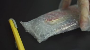 Kadınların eldivenli elleri baloncuklu ambalajdan renkli bardaklar çıkarır..