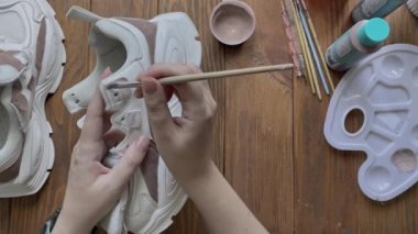 Düz kadın eli, ahşap masaya fırçayla beyaz çizme boyar..