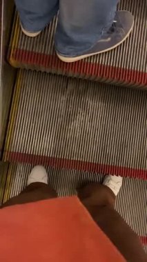 Yürüyen yürüyen yürüyen merdiven kullanan insanların ayakları üzerinden görünüm.