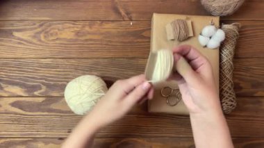 Kadınların elleri beyaz ipliği karton parçasına sarar.