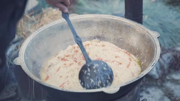 Person mischt Pilaf mit Schlitzlöffel in Kazan. — Stockvideo