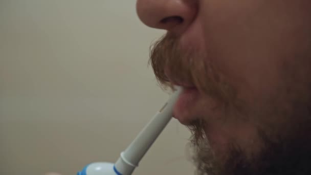 L'homme se brosse les dents avec une brosse à dents électrique. — Video