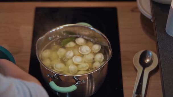 Mujer cocina pelmeni en bandeja de aluminio en la estufa de cocina de vidrio-cerámica — Vídeos de Stock