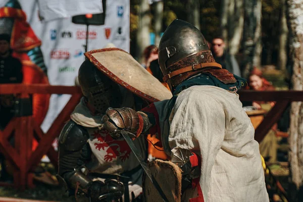 Dos caballeros con escudos luchan con espadas en la arena. — Foto de Stock