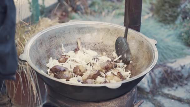 Chef mezcla carne y verduras en caldero grande con cuchara ranurada. — Vídeos de Stock