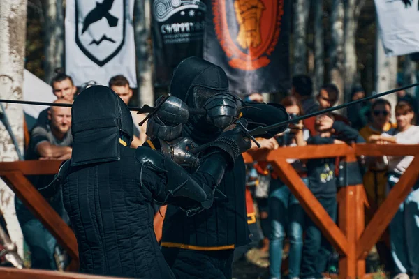 Dois cavaleiros de preto estão lutando na frente do público com espadas. — Fotografia de Stock