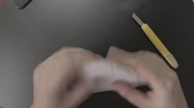 İnsanların elleri bir kırtasiye bıçağı alır ve paketi keser..