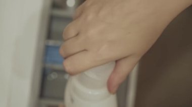 İnsan elleri sıvı beyaz durulamayı açar ve çamaşır makinesinin tepsisine döker. Ev temizliği ve hijyen. Ev işleri..