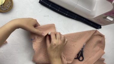 Kadınların elleri birbirine pamuklu gömleğin detaylarını iğnelerle tutturur. Dikiş makinesi olan bir moda tasarımcısı atölyesinin en iyi görüntüsü. Zanaat ve hobi.