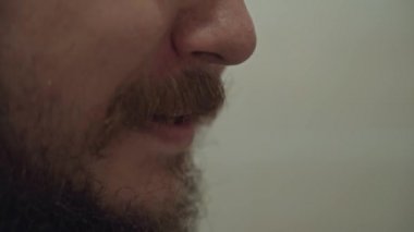Adam dişlerini diş ipiyle fırçalıyor. Sağlık için günlük rutin prosedür. Erkek yüzünde kalın bıyık ve sakal. Ağız temizliği..