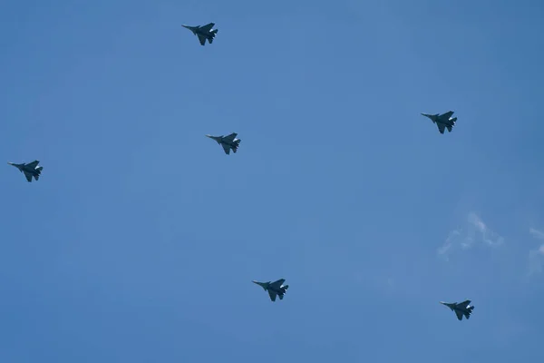 Victory parade of army air force over the city. Group of military aircraft shows aerobatics in blue sky against background of clouds. Representation of aviation equipment.