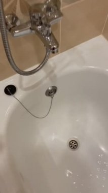 İnsan eli, küvetteki su borusunu kapatır. Zincirdeki lastik durdurucu. Kadın spa ameliyatı olurken dinlenmeye hazırlanıyor..