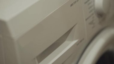 Çamaşır makinesindeki deterjan tepsisini kadın eli açıyor. Ev ödevi. Temizlik giysileri ve çarşaf için hazırlık. Toz, jel ve diğer sıvı ve kuru deterjanlar için plastik bölmeler.