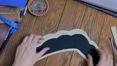 Dişilerin elleri tahta masaya etnik Slav tacı şeklinde bez seriyor. Terzi ve işyeri. Eko-deri ve birbirine yapışkan dokuma kumaştan yapılmış..