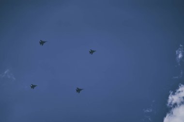 Şehre karşı askeri uçakların zafer geçit töreni. Havacılık ekipmanlarının temsili. Ordu hava kuvvetleri bulutların arka planına karşı mavi gökyüzünde akrobasi gösteriyor..