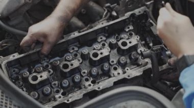 Maintenance worker fixes the car engine. installing the cylinder block head