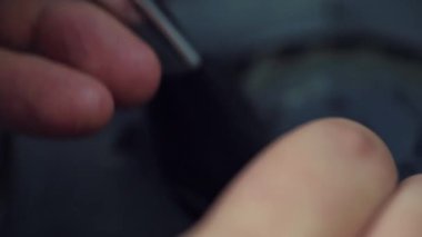 Repairman hands cleans dust in cooler system of gaming console or laptop during maintenance or prophylaxis, with dark brush in slowmotion. 
