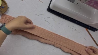 Terzinin elleri pamuk kumaşın detaylarını birbirine iğnelerle tutturur. Dikiş makinesi olan bir moda tasarımcısı atölyesinin en iyi görüntüsü. Zanaat ve hobi.