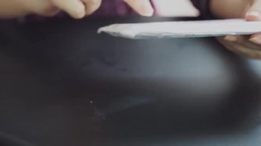 Kadın eli sabit bir bıçak alır ve paketi keser. İnternetten alışveriş. Posta kutuları. Siyah bir masanın üzerine bir paket açılıyor..