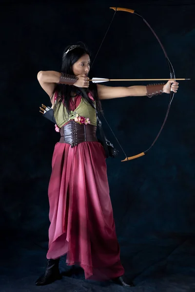 An elf (or other fantasy character) warrior woman wearing a laced bodice and draped skirt and holding a bow and arrow