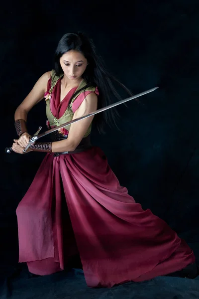 An elf (or other fantasy character) warrior woman wearing a laced bodice and draped skirt and holding a sword