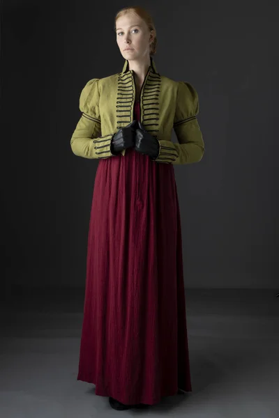 一位摄政女性穿着红色亚麻布衣服 戴着绿色的辫子和手套 衬托在工作室的背景下 — 图库照片