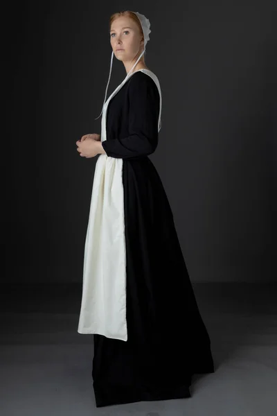 Een Amish Vrouw Met Een Zwarte Jurk Schort Pet Tegen — Stockfoto