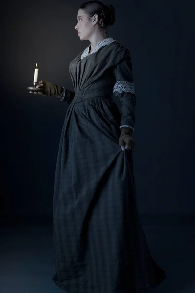 女佣人维多利亚时代的女佣或工人阶级妇女 身穿深绿色的格子裙和短裙 拿着蜡烛 — 图库照片