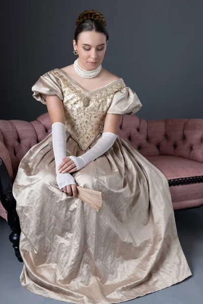 Victorian Woman Wearing Gold Ball Gown Sitting Pink Antique Sofa — Stockfoto