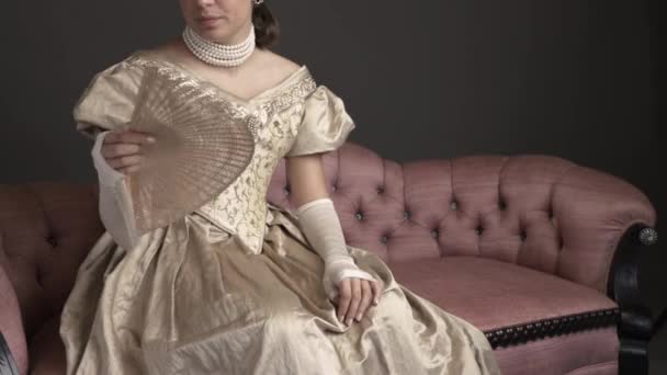 Eine Viktorianische Frau Trägt Ein Goldenes Ballkleid Und Sitzt Auf — Stockvideo