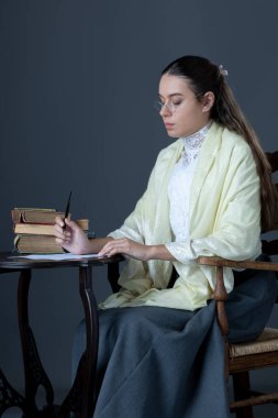 A Victorian or Edwardian woman sitting in a chair and reading a book