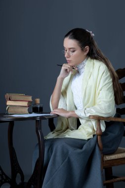 A Victorian or Edwardian woman sitting at a desk writing with an ink dip pen