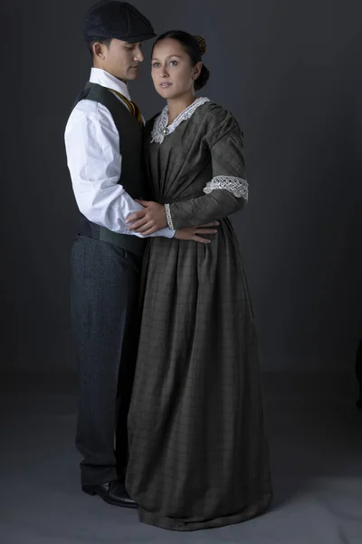 A romantic working class Victorian couple together against a grey studio backdrop