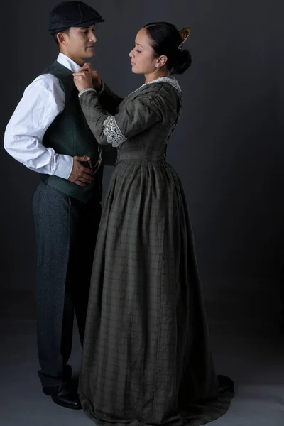 A romantic working class Victorian couple together against a grey studio backdrop