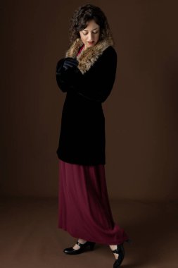 A 1920s woman wearing a black velvet coat with a fur collar