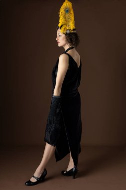 1920 'lerden bir kadın parti elbisesi ve tüylü bir saç bandı giyiyor.