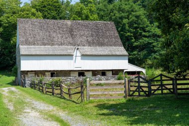 Çitlerle çevrili ahşap kiremitleri olan eski bir ahır..