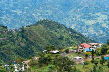 Tepenin kenarında küçük bir köy. Arkasında başka tepeler var..