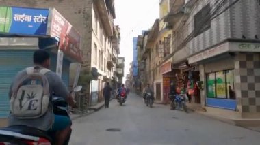 Katmandu, Nepal - 17 Ekim 2021: Nepal 'deki Katmandu şehrinin evleri arasında taştan bir kaldırım üzerinde araba sürmek.