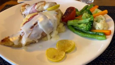 Yerel bir restoranda bir tabak ızgara balık saltimboca ve buharda pişmiş sebze..