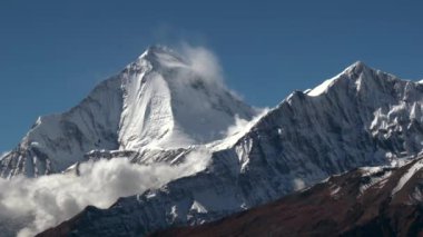 Nepal 'deki Himalayalar' da karla kaplı bir dağın üzerinden hızla geçen bulutlar..